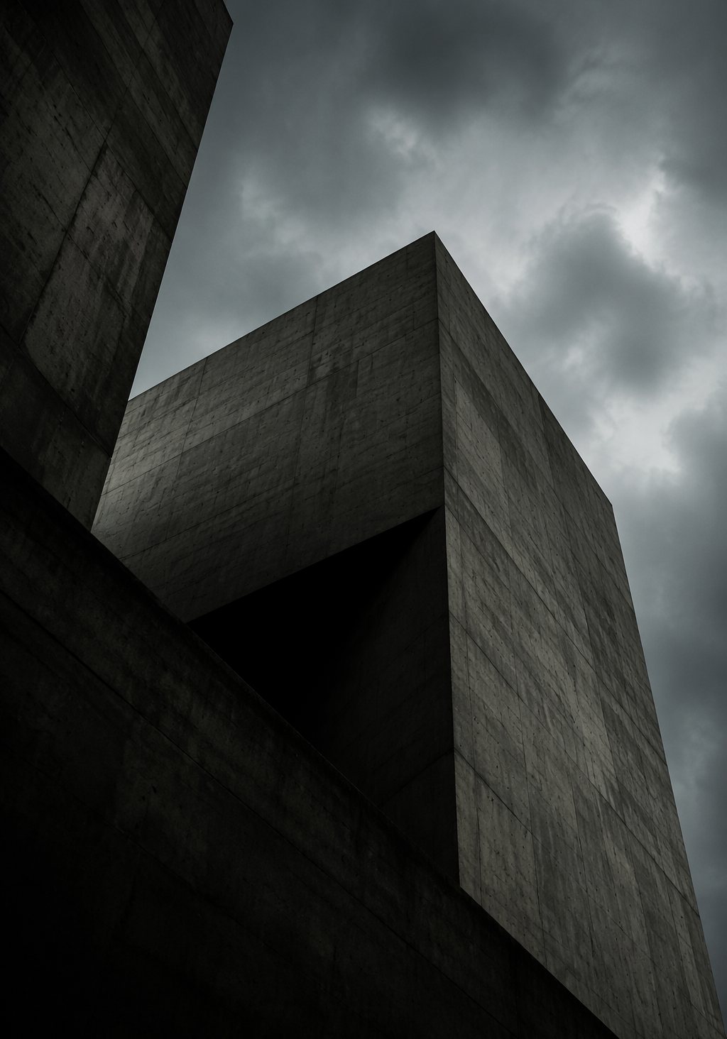 Brutalistische Betonarchitektur von unten fotografiert, dramatische Geometrie vor bewölktem Himmel